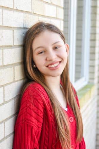 Teenage girl with straight teeth smiling outside after orthodontic treatment