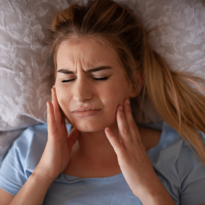 Woman in pain, holding jowls with both hands, representing bruxism