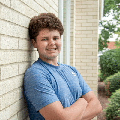 Teenage boy patient at maddux orthodontist smiles with arms crossed, representing orthodontic treatment in virginia beach va