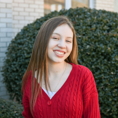 A girl wearing a red shirt smiling at camera, representing braces-friendly foods